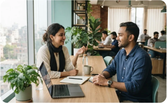 Two people discussing wellbeing across a table in a modern workplace